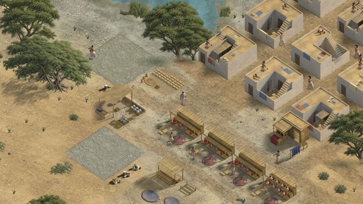 Pottery racks and kilns beside plastered houses, with trees and a pond.